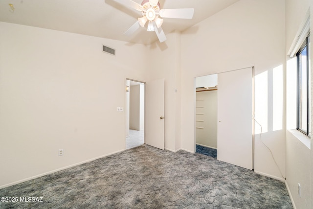 unfurnished bedroom featuring high vaulted ceiling, a closet, ceiling fan, and carpet flooring