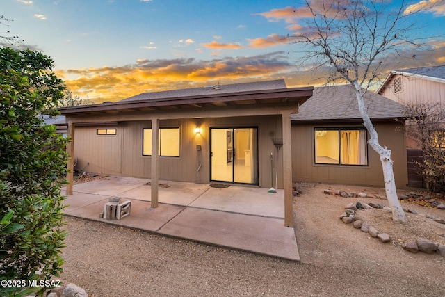 back house at dusk featuring a patio