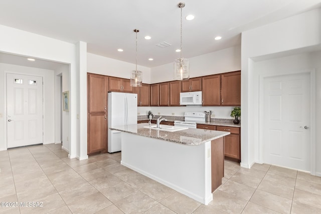 kitchen featuring pendant lighting, sink, a kitchen island with sink, light stone countertops, and white appliances