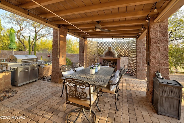 view of patio featuring ceiling fan, exterior fireplace, and a grill