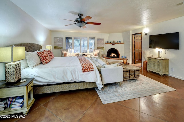 bedroom with ceiling fan and a large fireplace