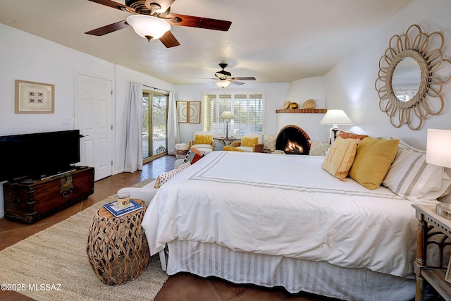 bedroom with a large fireplace, access to exterior, and ceiling fan