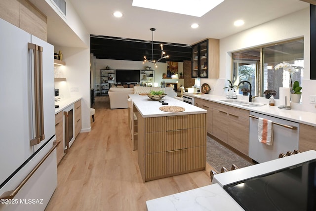 kitchen featuring a kitchen island, pendant lighting, sink, light wood-type flooring, and white appliances