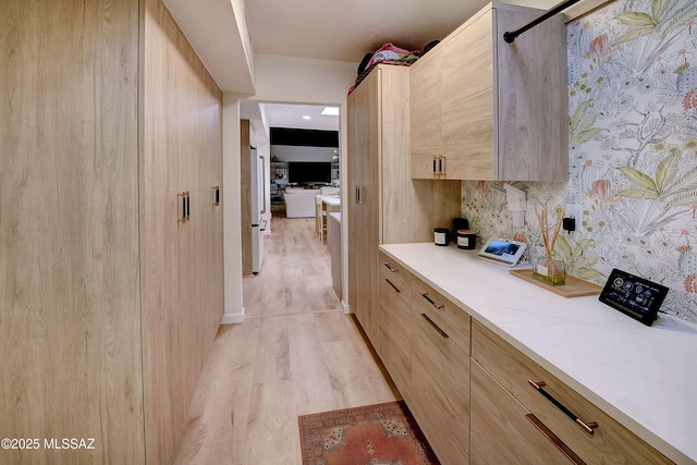 interior space featuring tasteful backsplash, light brown cabinetry, light hardwood / wood-style floors, and light stone countertops