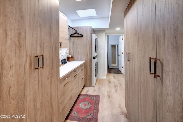 bathroom featuring walk in shower, stacked washer / drying machine, a skylight, vanity, and hardwood / wood-style floors