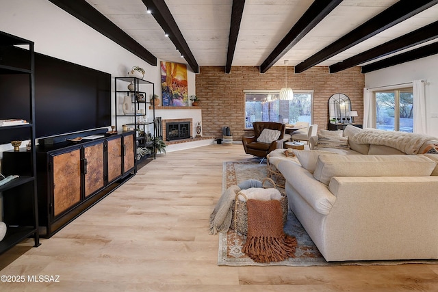 living room featuring light hardwood / wood-style flooring, beam ceiling, a fireplace, and brick wall