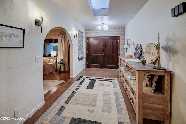 foyer entrance featuring hardwood / wood-style floors, a skylight, and a textured ceiling