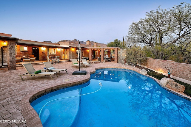 pool at dusk featuring outdoor lounge area and a patio area