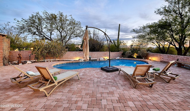 pool at dusk with a patio area