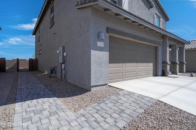 view of property exterior featuring concrete driveway, an attached garage, and stucco siding