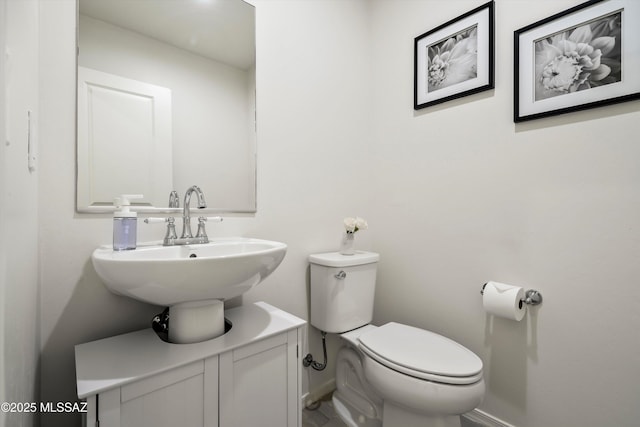 half bath featuring baseboards and toilet