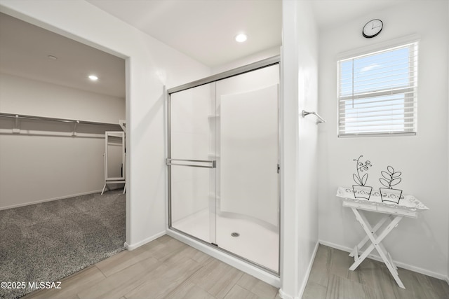 full bath featuring a stall shower, a walk in closet, and baseboards