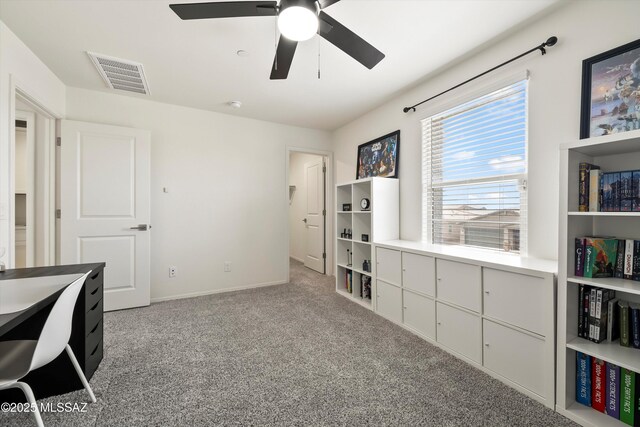 office space featuring light carpet, ceiling fan, visible vents, and baseboards