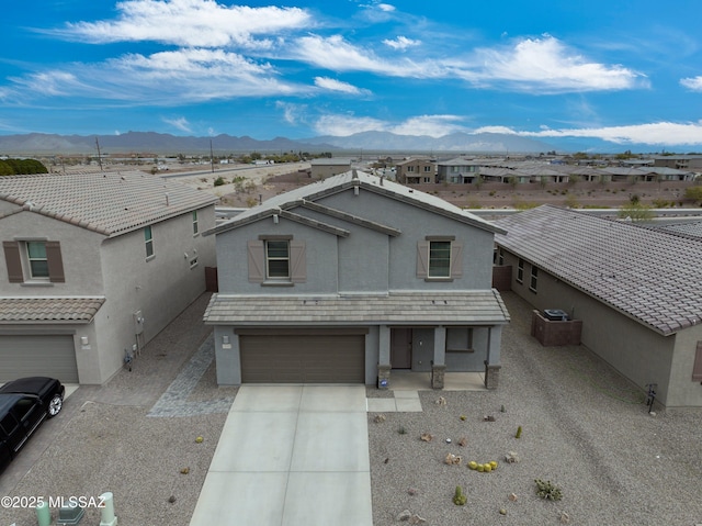 view of front of house with an attached garage, a mountain view, concrete driveway, and stucco siding