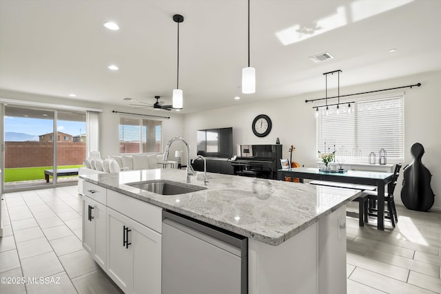 kitchen featuring visible vents, white cabinets, open floor plan, a kitchen island with sink, and a sink