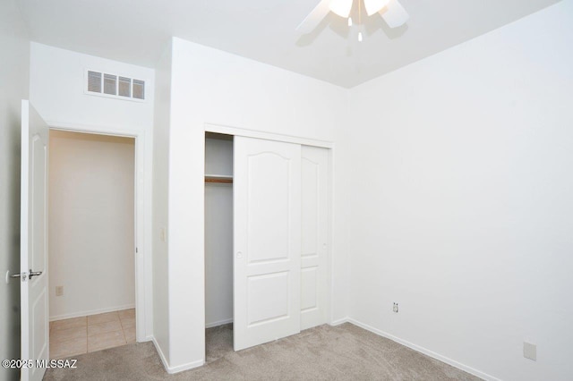 unfurnished bedroom featuring ceiling fan, light carpet, and a closet