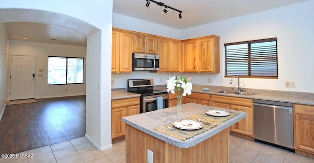 kitchen featuring light tile patterned floors, sink, light stone counters, a kitchen island, and stainless steel appliances