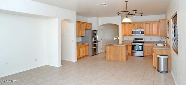 kitchen with sink, rail lighting, a center island, stainless steel appliances, and hanging light fixtures