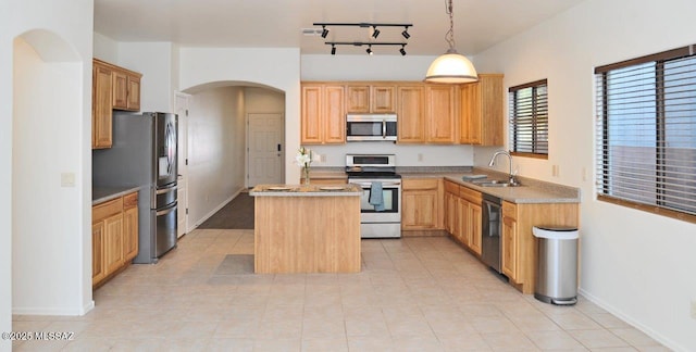 kitchen with an island with sink, decorative light fixtures, sink, light tile patterned floors, and appliances with stainless steel finishes