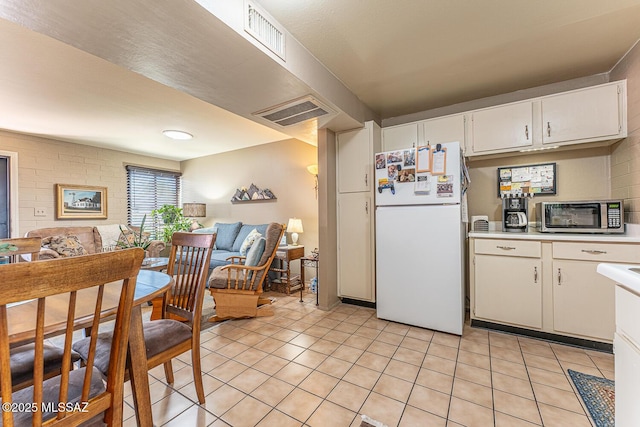 kitchen with light tile patterned floors, white cabinets, and white fridge