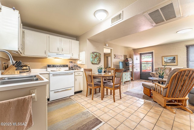 kitchen with light tile patterned flooring, white range with electric cooktop, sink, and white cabinets