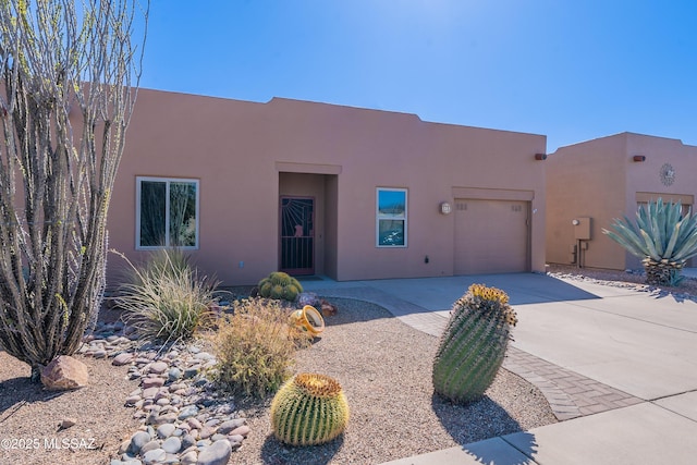 adobe home with stucco siding, concrete driveway, and an attached garage