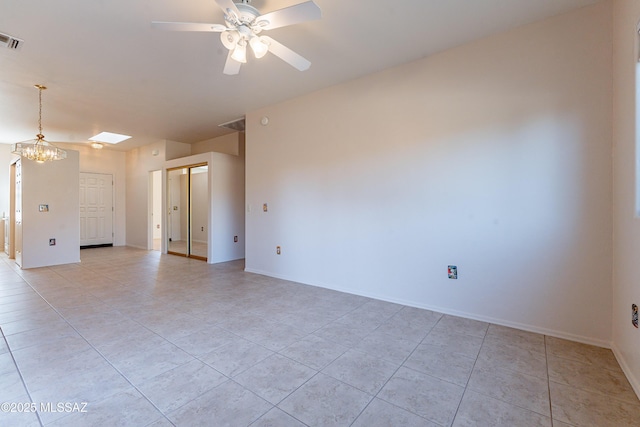 unfurnished room with light tile patterned floors, ceiling fan with notable chandelier, visible vents, and baseboards