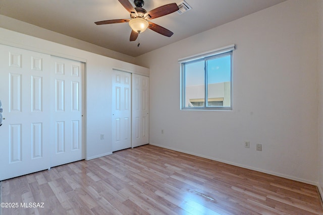 unfurnished bedroom with visible vents, two closets, a ceiling fan, light wood-style floors, and baseboards