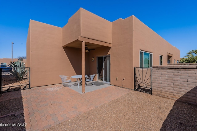 back of house with a patio, a ceiling fan, fence, and stucco siding