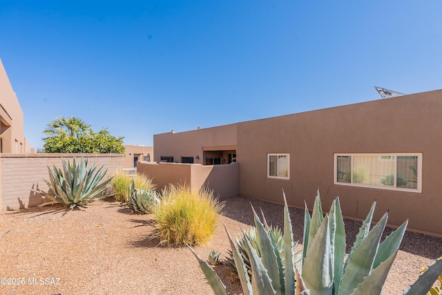 view of property exterior featuring stucco siding and fence