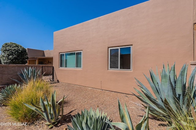 view of side of property with fence and stucco siding