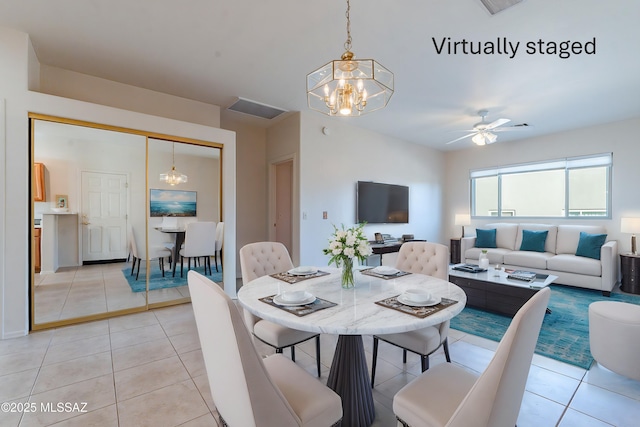 dining area featuring light tile patterned flooring and ceiling fan with notable chandelier