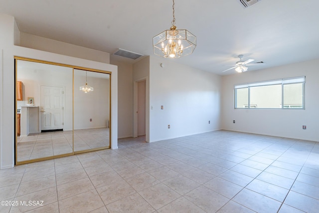 unfurnished room featuring light tile patterned floors, ceiling fan with notable chandelier, and baseboards