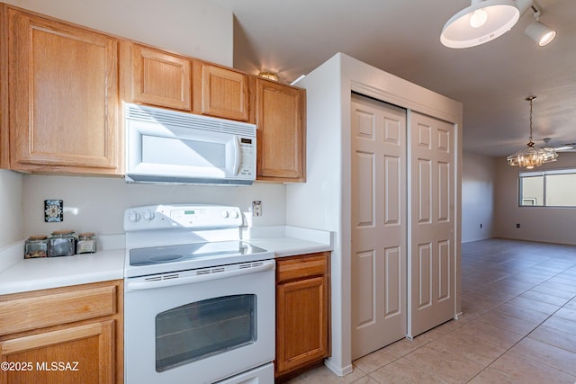 kitchen with light tile patterned floors, white appliances, a chandelier, and light countertops