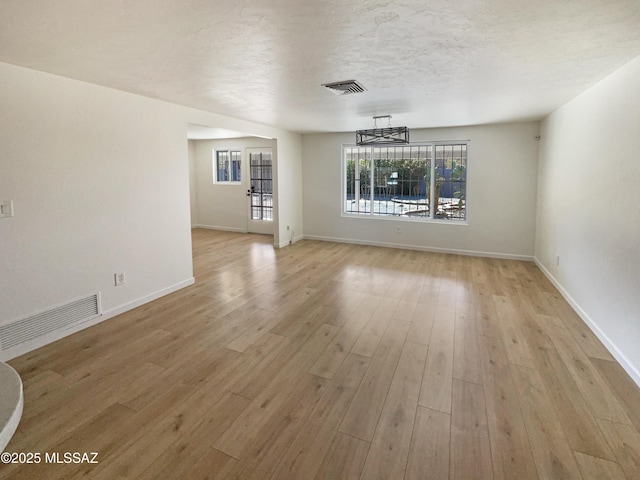 spare room with light hardwood / wood-style floors and a textured ceiling