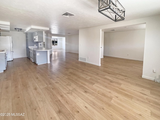 interior space featuring light wood-type flooring, white appliances, and kitchen peninsula