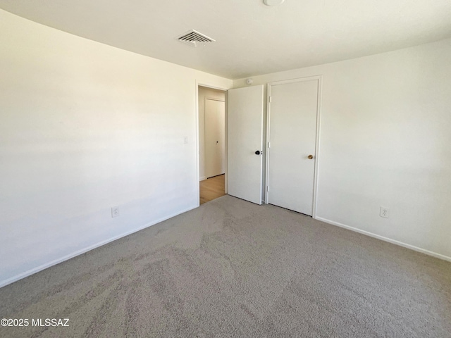 unfurnished bedroom with light colored carpet and a closet