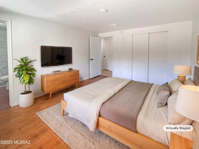 bedroom with wood-type flooring, ensuite bathroom, and a closet