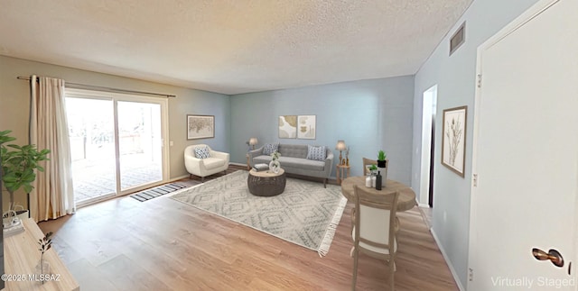 living area featuring light wood finished floors, baseboards, visible vents, and a textured ceiling