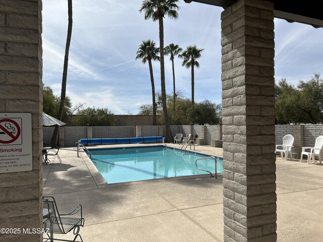 community pool with a fenced backyard and a patio
