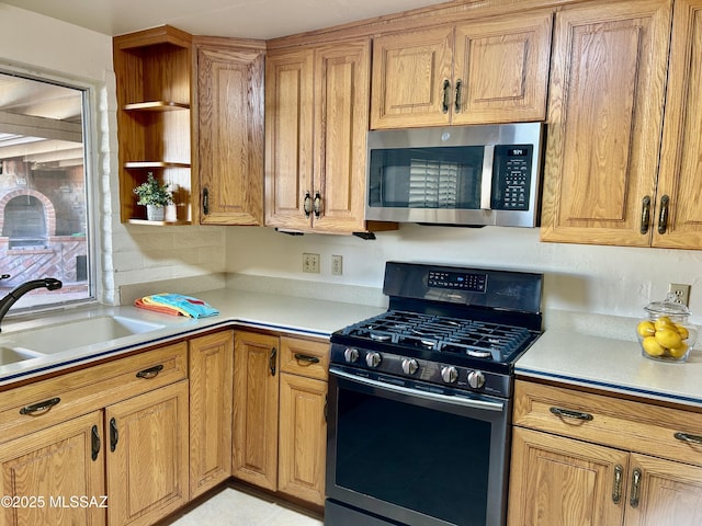 kitchen featuring open shelves, a sink, gas range, light countertops, and stainless steel microwave