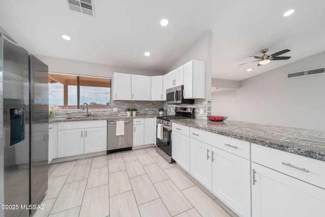 3098 S Giovanna Dr, Tucson, AZ 85730 - kitchen with appliances with stainless steel finishes, lofted ceiling, a sink, decorative backsplash, and white cabinetry