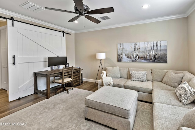 living room with ceiling fan, wood-type flooring, a barn door, and crown molding