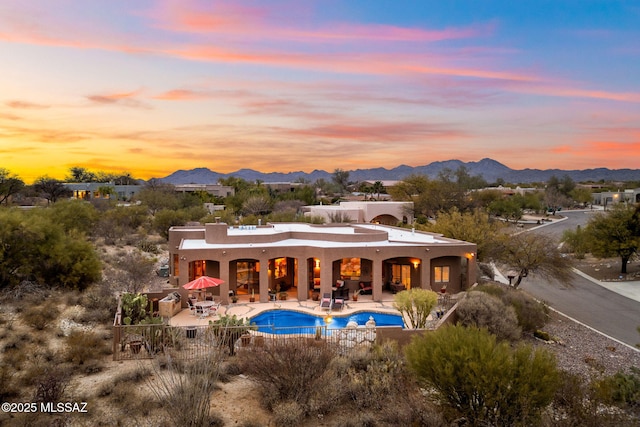 back house at dusk with a mountain view and a patio