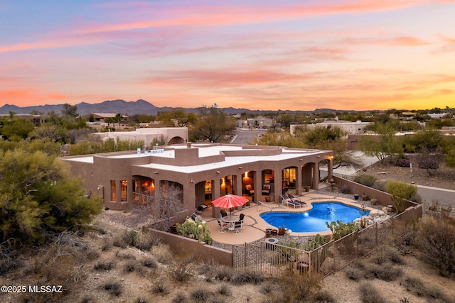 back house at dusk with a fenced in pool, a mountain view, and a patio area