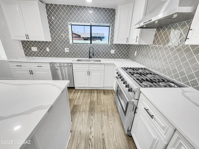 341 S Tucson Blvd, Tucson, AZ 85716 - kitchen featuring wall chimney range hood, a sink, light wood-type flooring, stainless steel appliances, and white cabinets