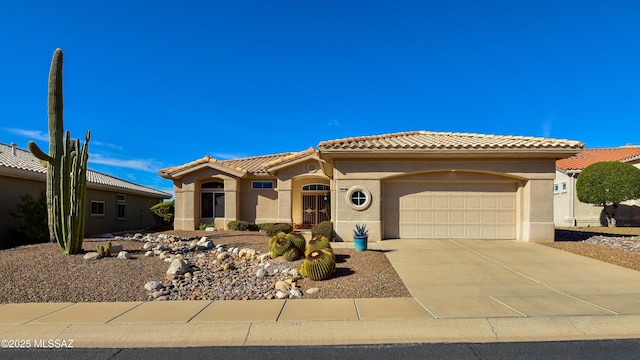 mediterranean / spanish-style house featuring a garage, a tile roof, concrete driveway, and stucco siding