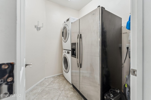 washroom with baseboards, stacked washer and clothes dryer, light tile patterned flooring, and laundry area