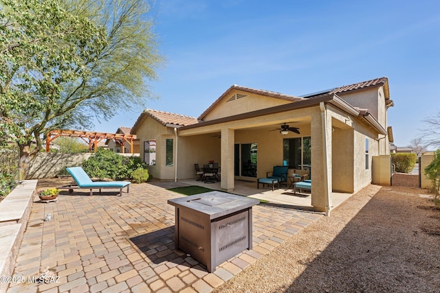 rear view of house featuring a patio area, stucco siding, a ceiling fan, and fence