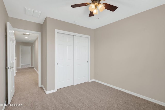 unfurnished bedroom featuring ceiling fan, light colored carpet, and a closet